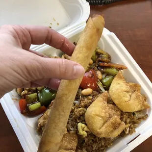 a hand grabbing a piece of food from a styrofoam container