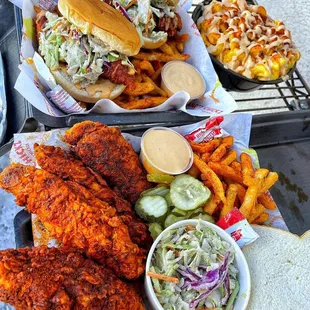 two trays of fried chicken, fries and coleslaw