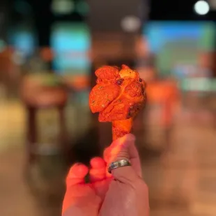 a hand holding a piece of fried chicken