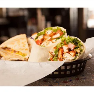 a wrap of chicken, lettuce, tomato, and cheese