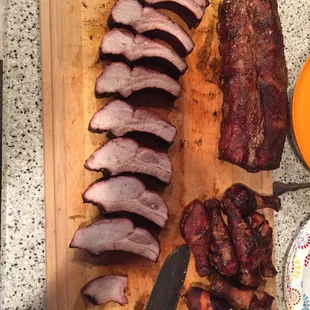 a wooden cutting board with sliced meats