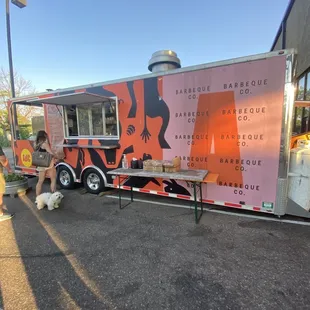 a woman walking her dog in front of a food truck