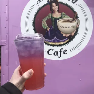 Butterfly lemonade drink in front of cafe sign.