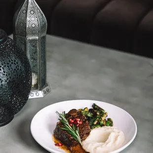 Braised short rib with a pomegranate reduction, served with a cauliflower puree and Brussels sprouts.