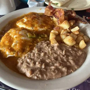 Huevos rancheros plate. Crispy bacon, potatoes and refried beans  Homemade tortillas