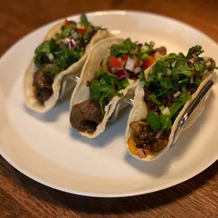 three tacos on a white plate