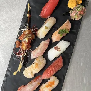 a variety of sushi on a black plate