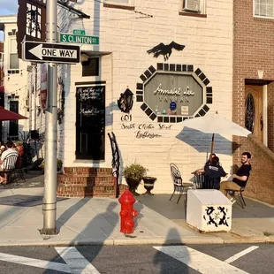 people sitting at tables on the sidewalk