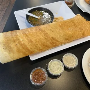 A marsala dosa with sambar and coconut chutney, peanut chutney, tomato chutney