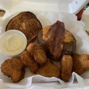 a burger and tater tots in a styrofoam container