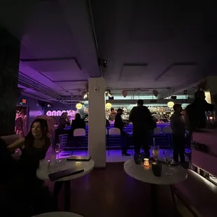 people sitting at tables in a dimly lit bar