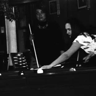 two people playing pool in a dark room