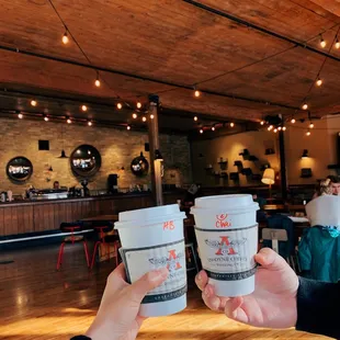 two people holding coffee cups