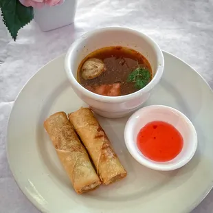 a bowl of soup and two spring rolls