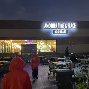 two people walking in front of a restaurant