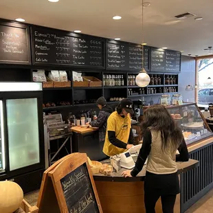 two people standing at a counter in a coffee shop