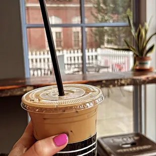 a hand holding a cup of iced coffee