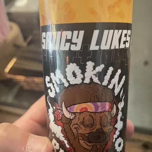 a hand holding a bottle of hot sauce