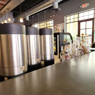 stainless steel tanks on a counter in a coffee shop