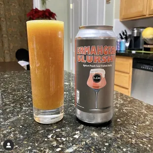 a glass of orange juice next to a can
