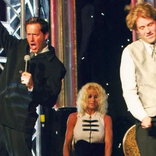 a man in a tuxedo singing on stage