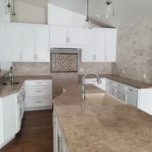 a kitchen with white cabinets and marble countertops