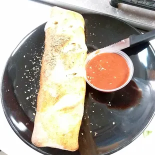 a piece of bread on a plate with dipping sauce