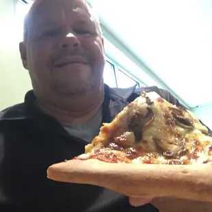 a man holding a slice of pizza