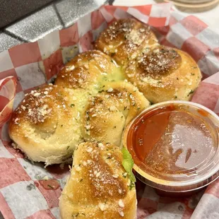 a basket of bread rolls with dipping sauce