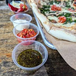 Condiments including olive oil and black pepper, Calabrian chili paste, Parmesan cheese, Calabrian chilis, minced garlic.