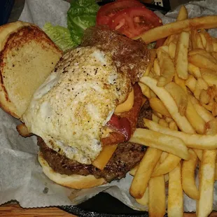 The Gladstoner, consisting of a beef patty, American cheese, cheese sauce, topped with a fried egg, bacon, onion ring, tomato, lettuce.