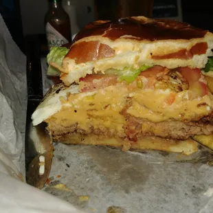 The Gladstoner, consisting of a beef patty, American cheese, cheese sauce, topped with a fried egg, bacon, onion ring, tomato, lettuce.