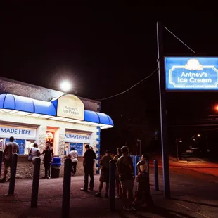 a group of people standing outside of a restaurant at night