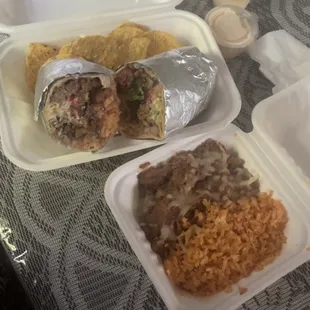 Side of rice and beans, and a perfectly packed burrito with some chips
