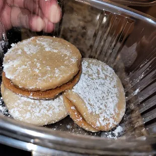 a person putting powdered sugar on cookies