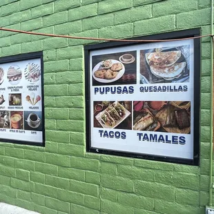a green brick wall with posters on it