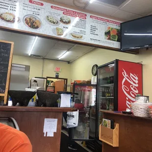 a restaurant counter with a menu on the wall