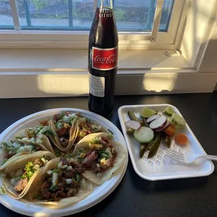 a bottle of coke and a plate of tacos