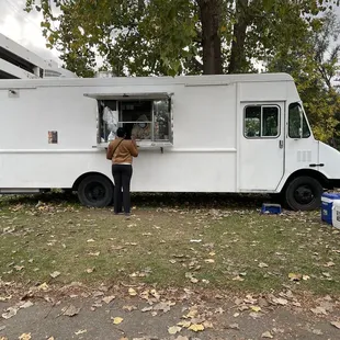 a woman standing in front of a food truck