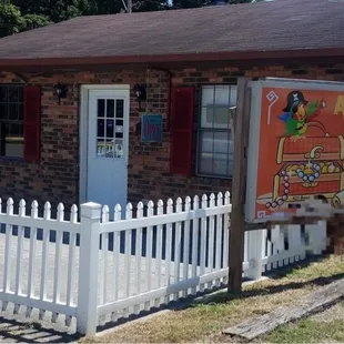 a small brick building with a white picketer and a white fence