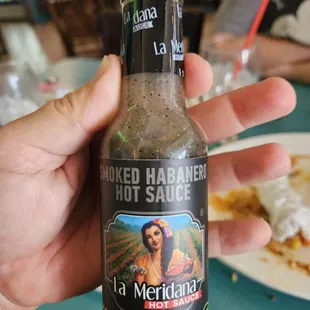 a hand holding a bottle of hot sauce