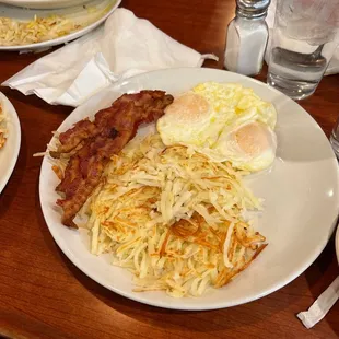 a plate of eggs, hash browns, bacon, and hash browns