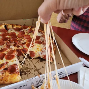 a hand holding a slice of pepperoni pizza