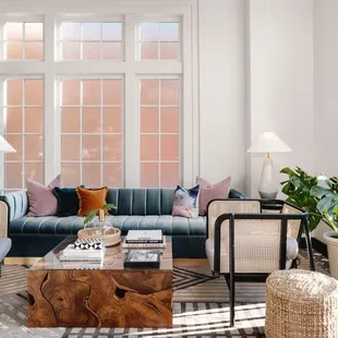 a living room with a couch, coffee table, chairs, and potted plants