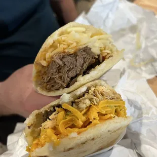 a person holding a sandwich with meat and cheese