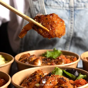 a person holding chopsticks above a bowl of food