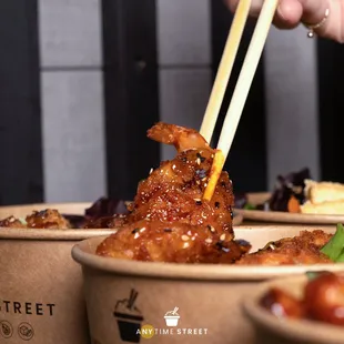 a person holding chopsticks over a bowl of food