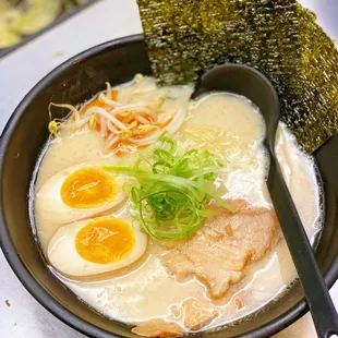 a bowl of ramen with an egg and a piece of seaweed