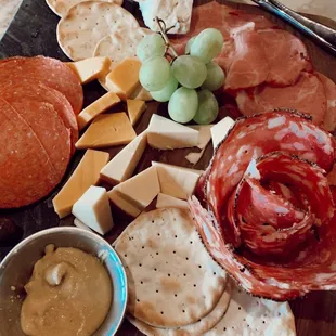 a platter of cheese, crackers, crackers, and grapes