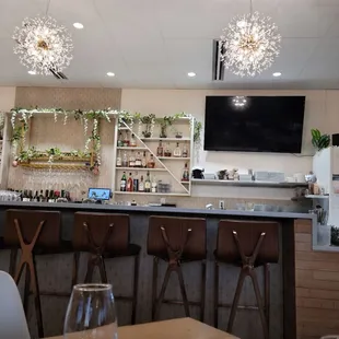 a view of a bar with chairs and a television
